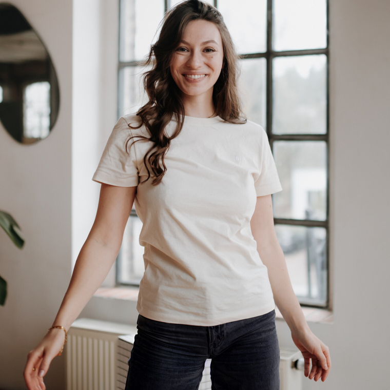 Frau trägt das T-Shirt Alva zu Jeans in einer Wohnung am Fenster