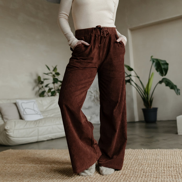 Frau trägt die Cord Sweathose Lana in Kastanienbraun mit cremefarbenem Rippshirt