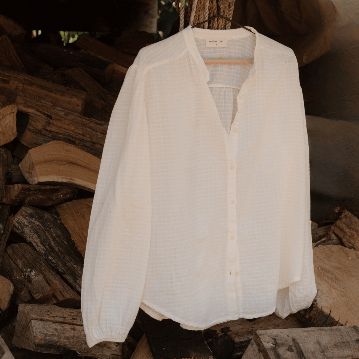 Boho Bluse Hilda, aufgehängt vor Feuerholz