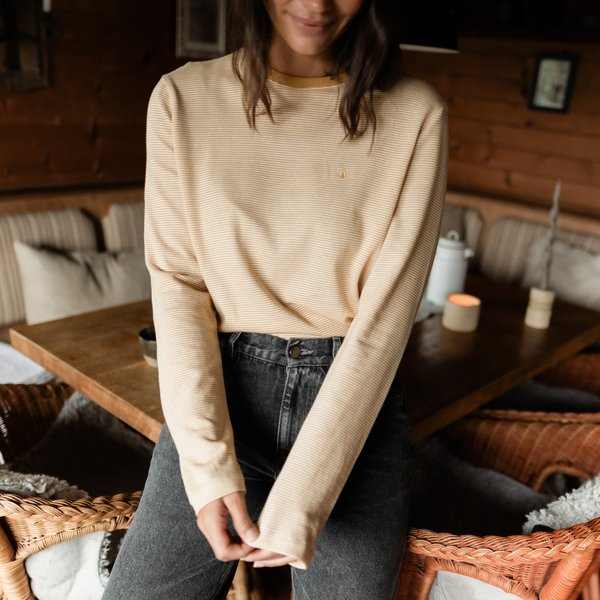Frau trägt das Gestreiftes Oversize Langarmshirt Alva in Gelb mit grauer Jeans