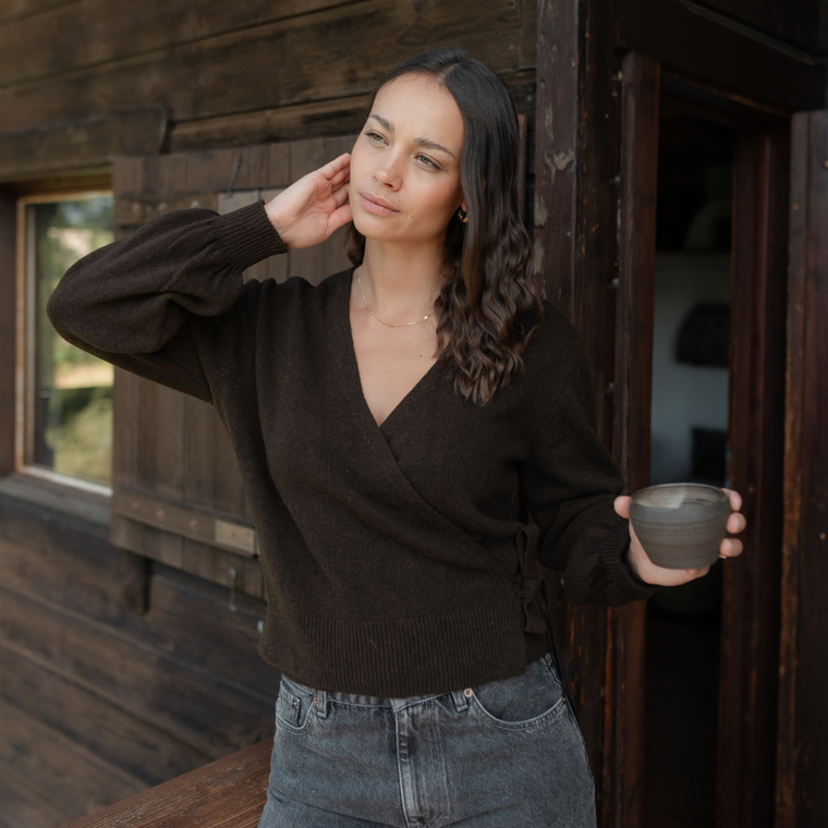Wickelcardigan Mona, Nahaufnahme mit Tasse in der Hand vor dunkler Holzwand